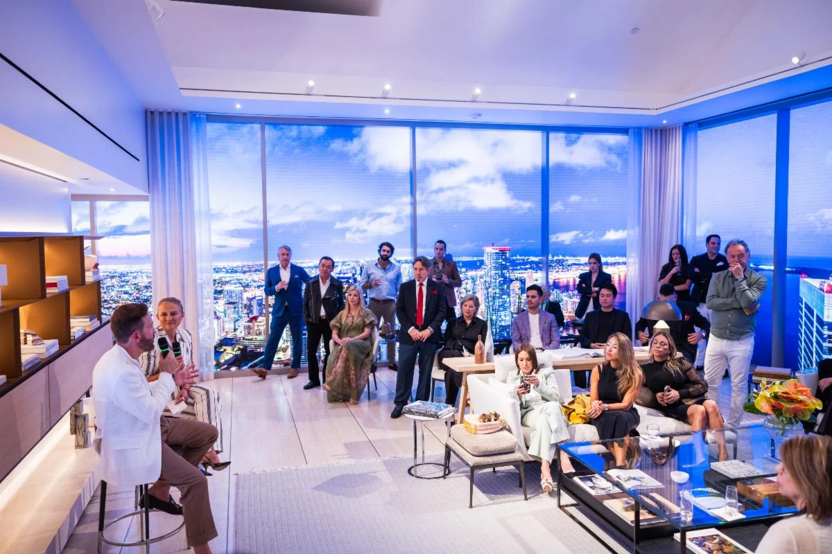 Daniel Novela speaking to a group of distinguished people in a luxury high-rise condo.